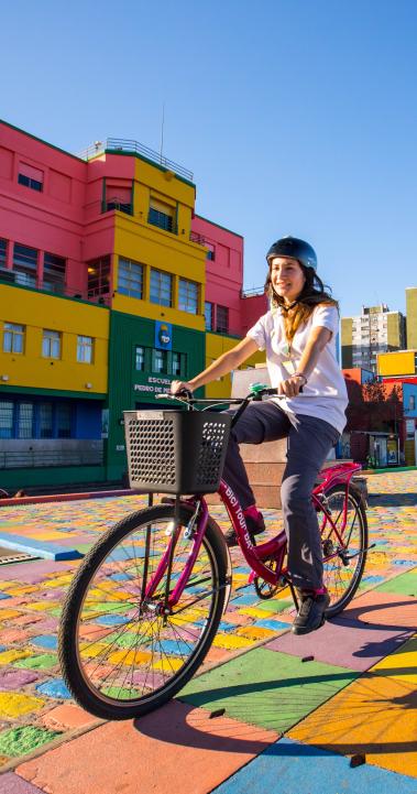 A student riding a bike through the colorful neighborhood of La Boca