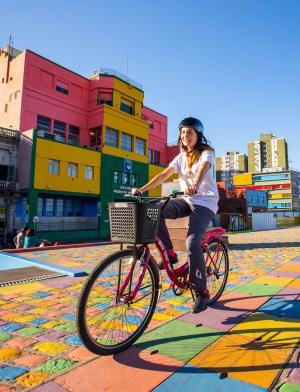 A student riding a bike through the colorful neighborhood of La Boca