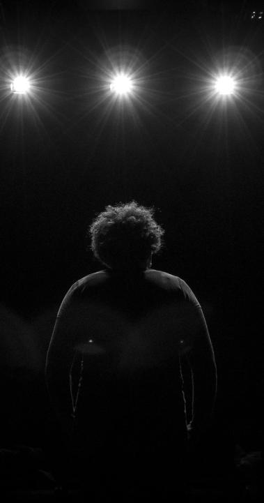 a student standing on stage facing the spotlights