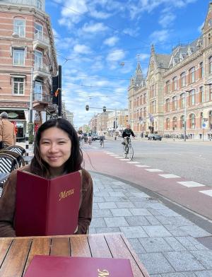 a student sitting on an outdoor restaurant patio with a menu in Amsterdam
