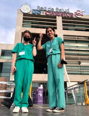 two female students in scrubs pose for a photo outside of their clinical observation